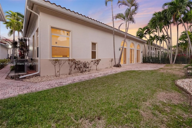 property exterior at dusk featuring central AC unit and a yard