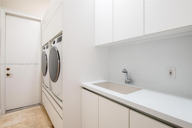 laundry area with cabinets, washing machine and dryer, and sink