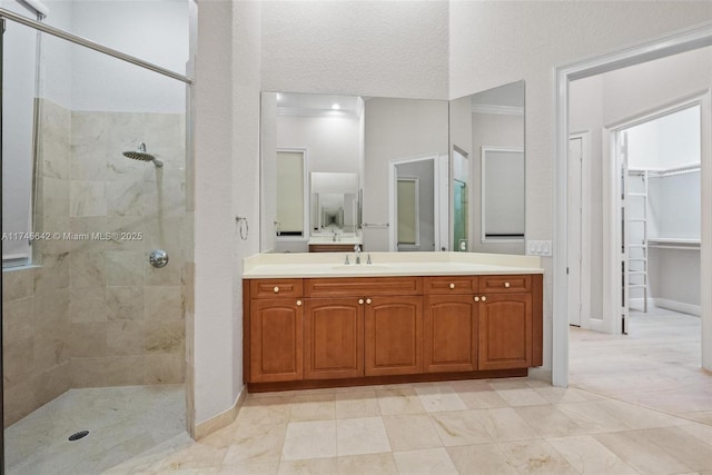 bathroom with vanity, a tile shower, a textured ceiling, and crown molding