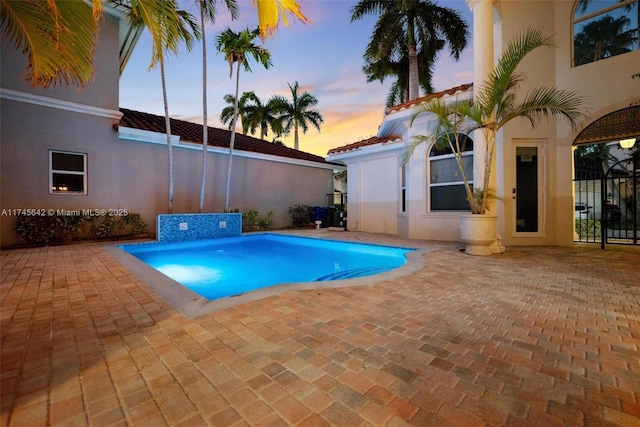 pool at dusk with a patio area