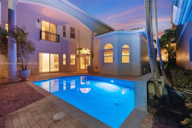 pool at dusk featuring a patio