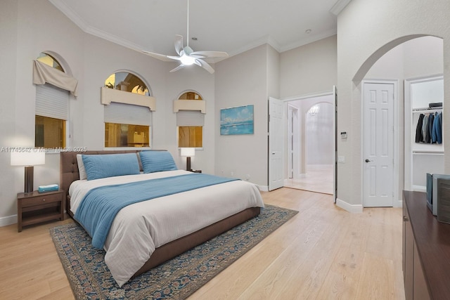 bedroom featuring ornamental molding, light hardwood / wood-style flooring, and a high ceiling