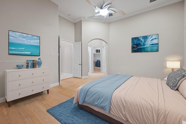 bedroom featuring crown molding, a towering ceiling, ceiling fan, and light hardwood / wood-style flooring