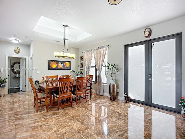 dining area featuring a tray ceiling, a skylight, french doors, and a textured ceiling