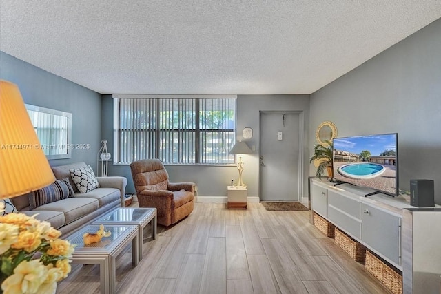 living room with plenty of natural light, a textured ceiling, and light wood-type flooring