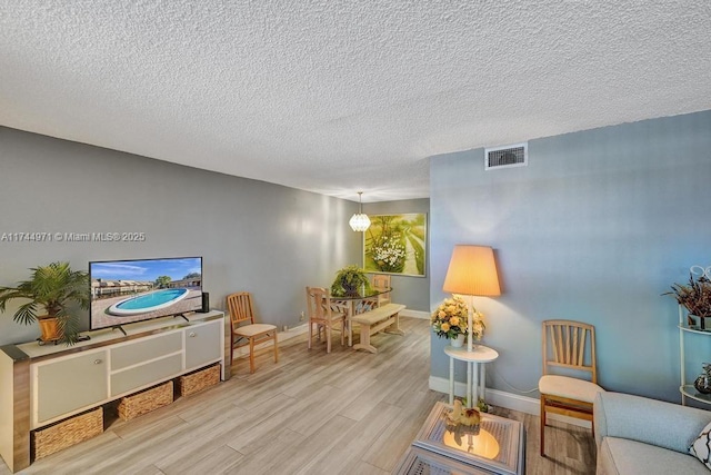 living area with a textured ceiling and light wood-type flooring