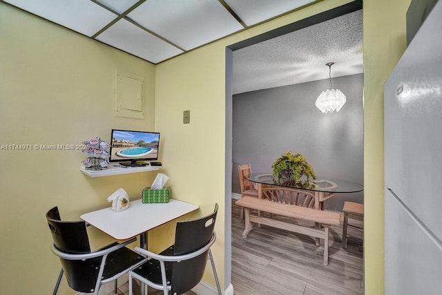 dining space featuring wood-type flooring, a notable chandelier, and a textured ceiling