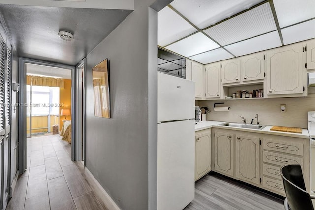 kitchen with white refrigerator, sink, tasteful backsplash, and light wood-type flooring