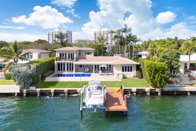 rear view of property with boat lift, a water view, a patio area, and an outdoor pool