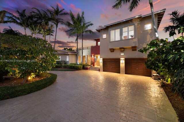 mediterranean / spanish-style home with curved driveway, a garage, and stucco siding
