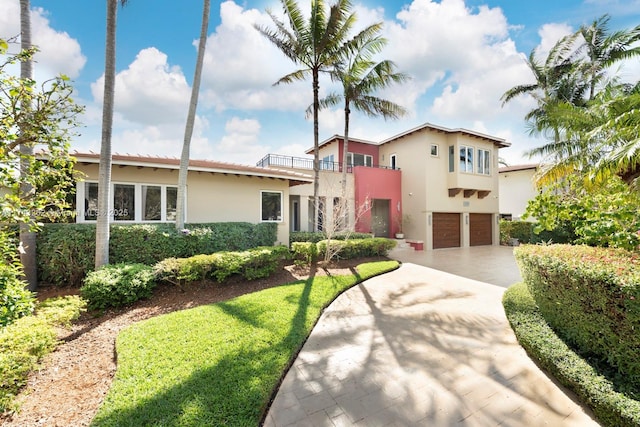 mediterranean / spanish home featuring a garage, driveway, a balcony, and stucco siding