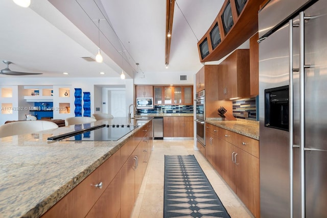 kitchen with brown cabinets, light stone counters, built in appliances, decorative backsplash, and visible vents