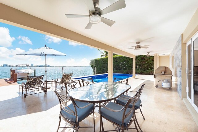 view of patio / terrace featuring exterior kitchen, a water view, a ceiling fan, and outdoor dining space