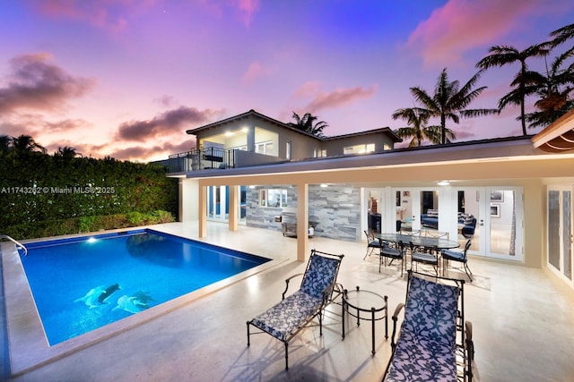 pool at dusk featuring a patio area and an outdoor pool