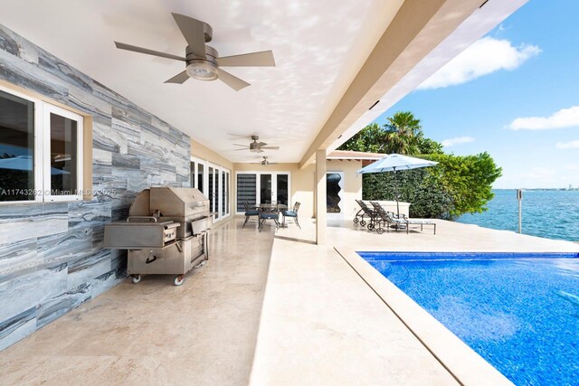 pool featuring ceiling fan, french doors, an outdoor kitchen, a patio area, and a water view