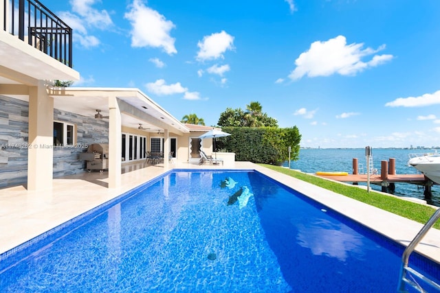 outdoor pool featuring ceiling fan, grilling area, a patio, a dock, and a water view