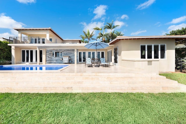 rear view of house featuring a balcony, a patio, an outdoor pool, stucco siding, and french doors