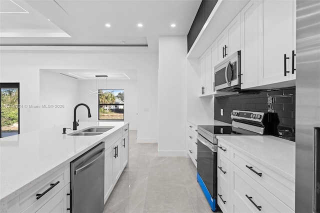 kitchen with sink, light stone counters, tasteful backsplash, appliances with stainless steel finishes, and white cabinets