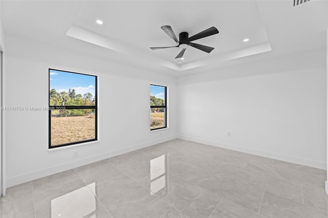 spare room with a tray ceiling and ceiling fan