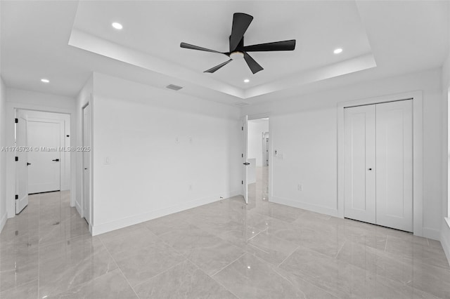 unfurnished bedroom with a raised ceiling and ceiling fan