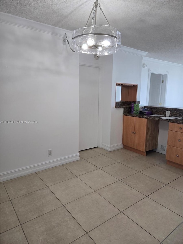 unfurnished dining area featuring crown molding, a textured ceiling, and light tile patterned flooring