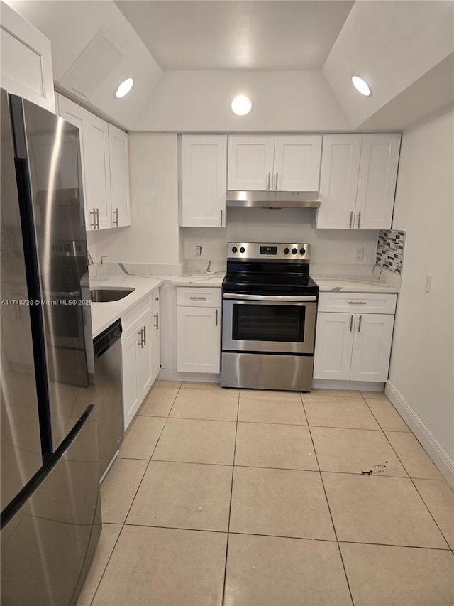 kitchen with stainless steel appliances, white cabinetry, lofted ceiling, and light tile patterned floors