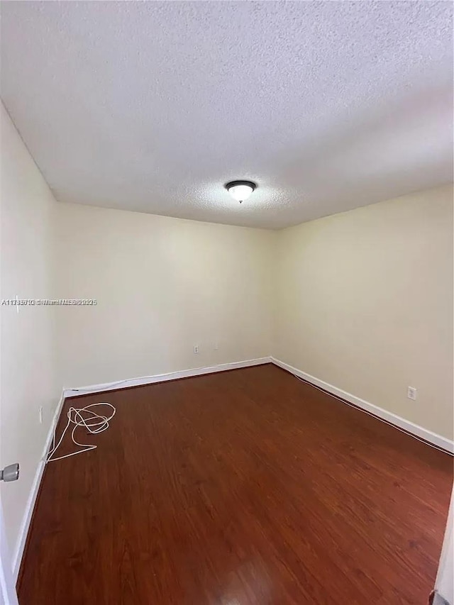 unfurnished room with wood-type flooring and a textured ceiling