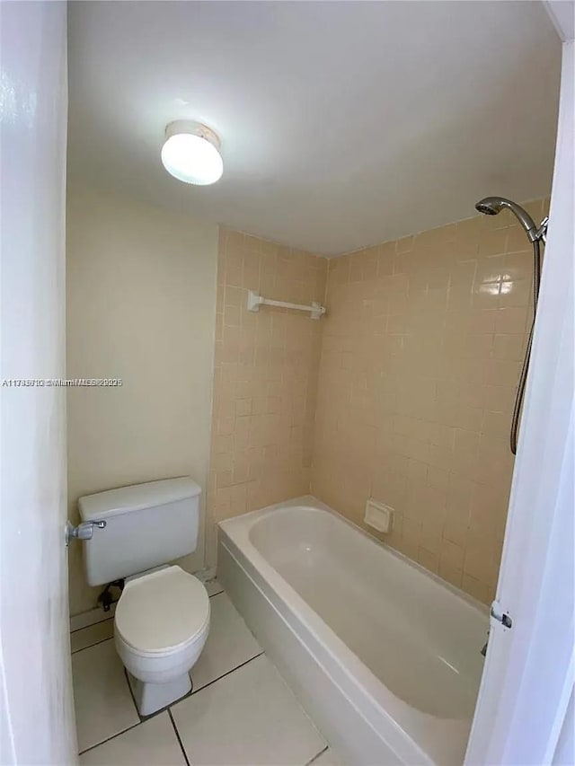 bathroom with tile patterned flooring, tiled shower / bath, and toilet