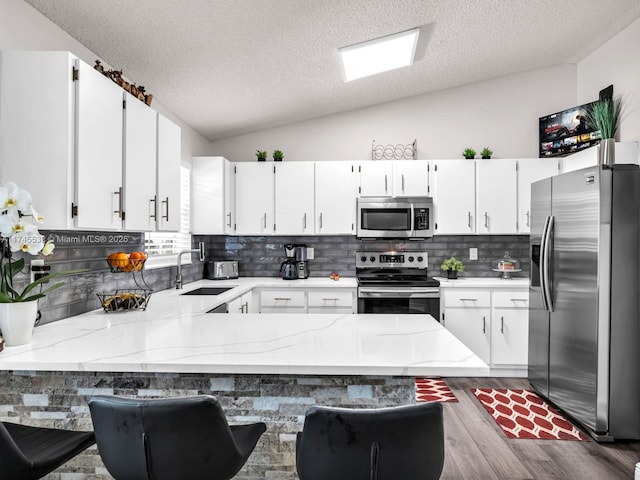 kitchen featuring appliances with stainless steel finishes, white cabinetry, and a peninsula