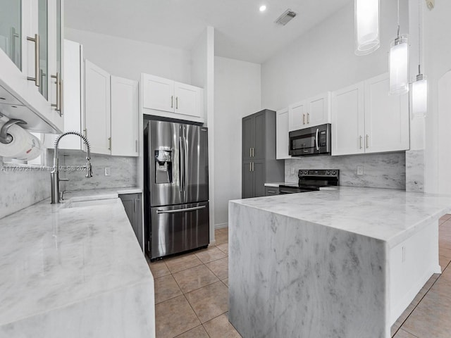 kitchen with decorative light fixtures, sink, white cabinets, stainless steel appliances, and light stone countertops