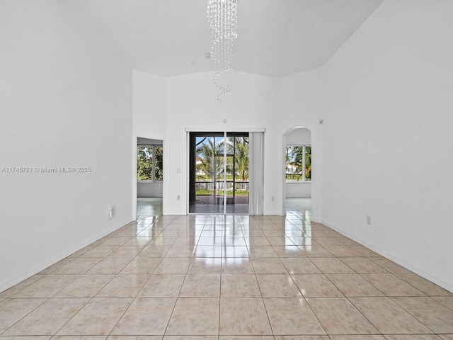 unfurnished room with an inviting chandelier, a high ceiling, and light tile patterned floors