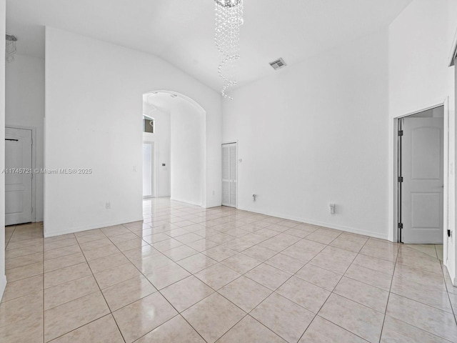 empty room with light tile patterned flooring and high vaulted ceiling