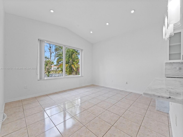 tiled spare room featuring lofted ceiling