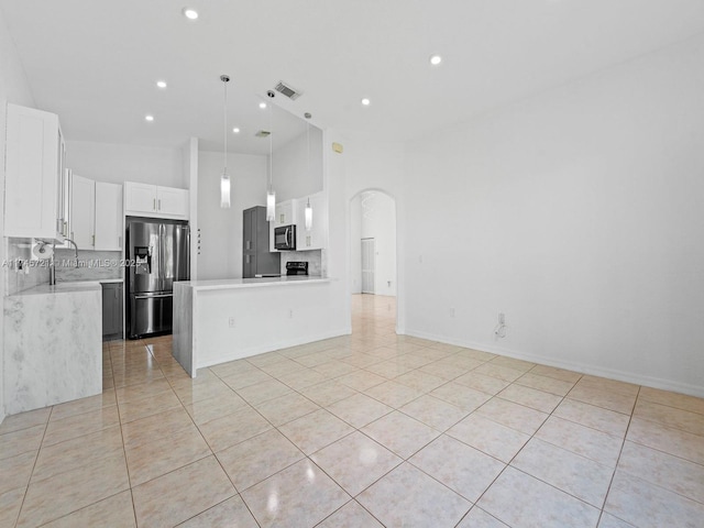 kitchen with white cabinetry, stainless steel fridge, decorative backsplash, hanging light fixtures, and light tile patterned floors