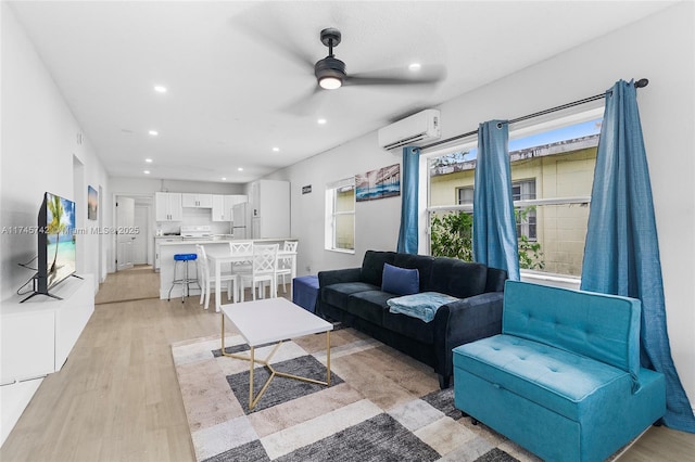 living room featuring a wall mounted air conditioner, ceiling fan, and light hardwood / wood-style flooring