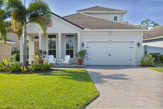 view of front of house with covered porch, decorative driveway, board and batten siding, and a front yard