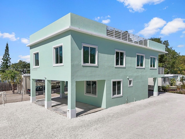 back of property featuring fence, a patio area, a carport, and stucco siding