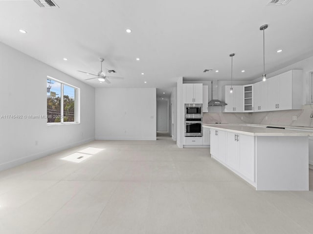 kitchen featuring wall chimney range hood, stainless steel appliances, light countertops, and recessed lighting
