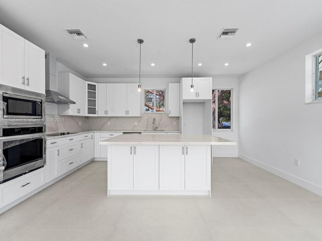 kitchen featuring wall chimney exhaust hood, a sink, tasteful backsplash, light countertops, and appliances with stainless steel finishes