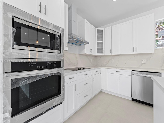 kitchen with wall chimney exhaust hood, appliances with stainless steel finishes, and white cabinetry