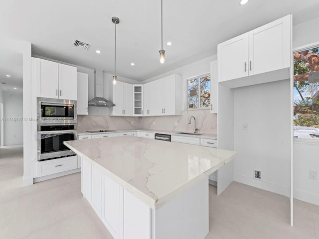 kitchen featuring a sink, visible vents, backsplash, wall chimney range hood, and appliances with stainless steel finishes