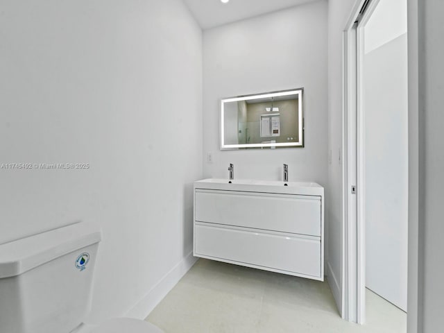 full bath featuring double vanity, toilet, and baseboards