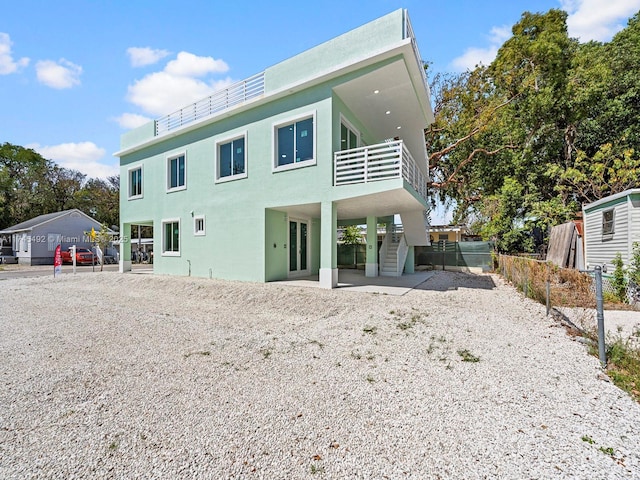 rear view of property with stairway, a patio, and fence