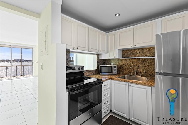 kitchen featuring sink, light tile patterned floors, appliances with stainless steel finishes, tasteful backsplash, and white cabinets