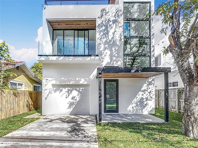 modern home featuring a garage, a balcony, and a front lawn