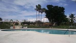 community pool with a patio area and fence