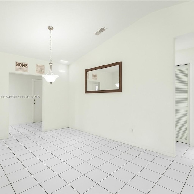 empty room featuring visible vents, light tile patterned floors, and vaulted ceiling