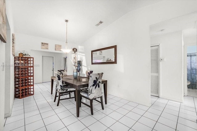 dining room featuring visible vents, light tile patterned floors, and vaulted ceiling