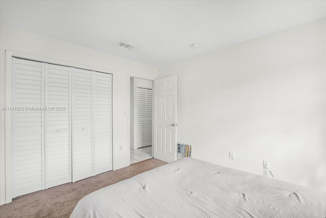 carpeted bedroom featuring a closet and visible vents