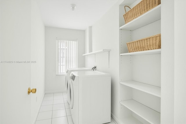 clothes washing area with light tile patterned floors, washer and dryer, laundry area, and baseboards